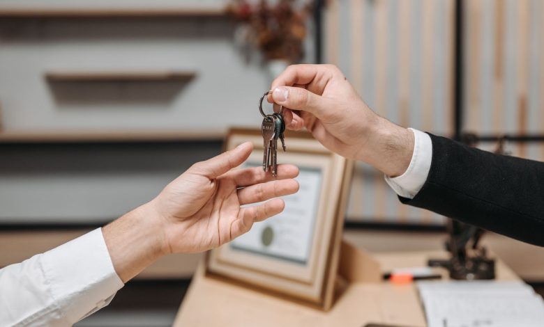 Detailed view of hands exchanging keys in a professional office environment, symbolizing real estate or business transactions.