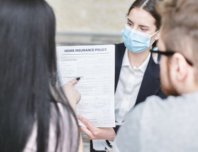 A professional woman explains a home insurance policy to clients during a meeting. Indoors setting.