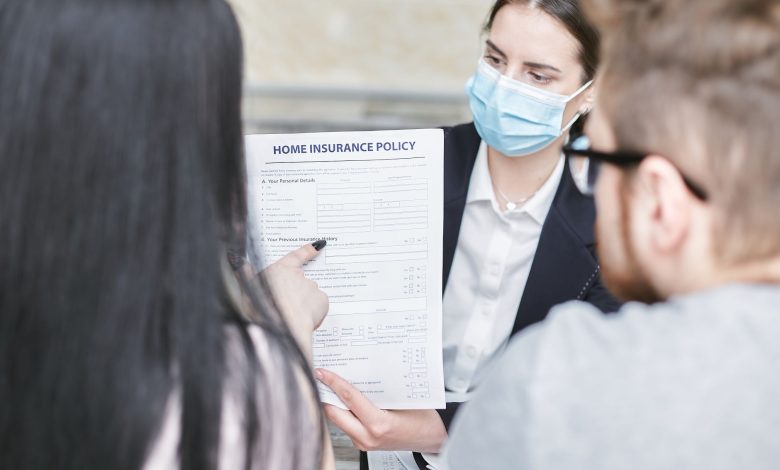 A professional woman explains a home insurance policy to clients during a meeting. Indoors setting.