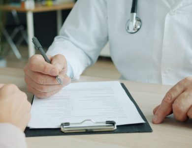 Close-up of doctor and patient reviewing medical documents during consultation.