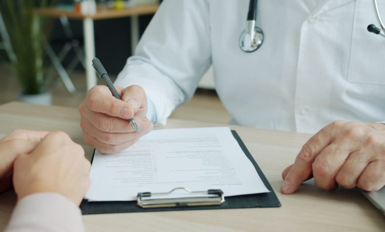 Close-up of doctor and patient reviewing medical documents during consultation.