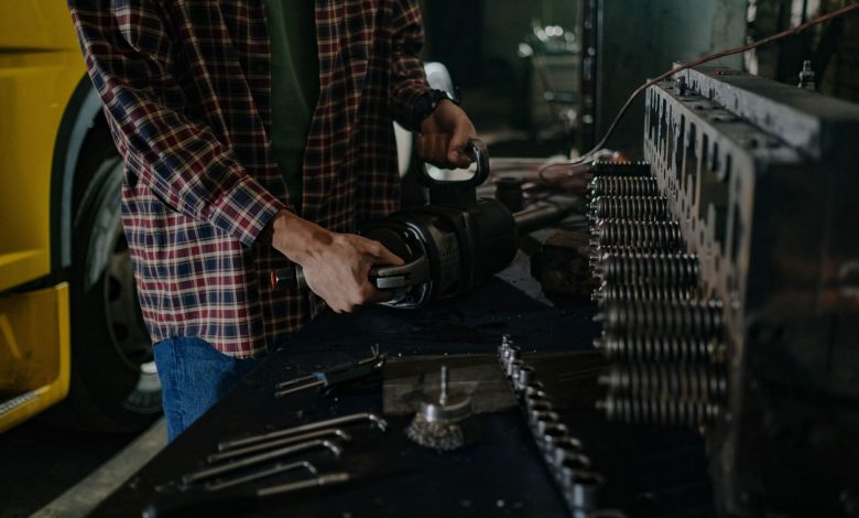 Mechanic using tools in an auto repair workshop for vehicle maintenance.