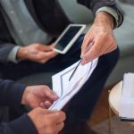 Close-up of two business professionals discussing documents in a meeting.